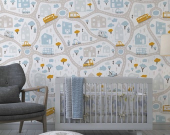 May include: A nursery scene with a gray cot and blue and white bedding. The wallpaper features a repeating pattern of roads, houses, trees, and vehicles in blue, yellow, and grey. A grey armchair and patterned ottoman are in the foreground. The wallpaper is the focal point.