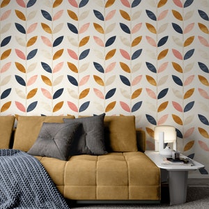 Puede incluir: Un sof&aacute; marr&oacute;n con dos almohadas grises y una manta de punto gris delante. El sof&aacute; est&aacute; delante de una pared con un patr&oacute;n repetitivo de hojas rosas, naranjas y azules.