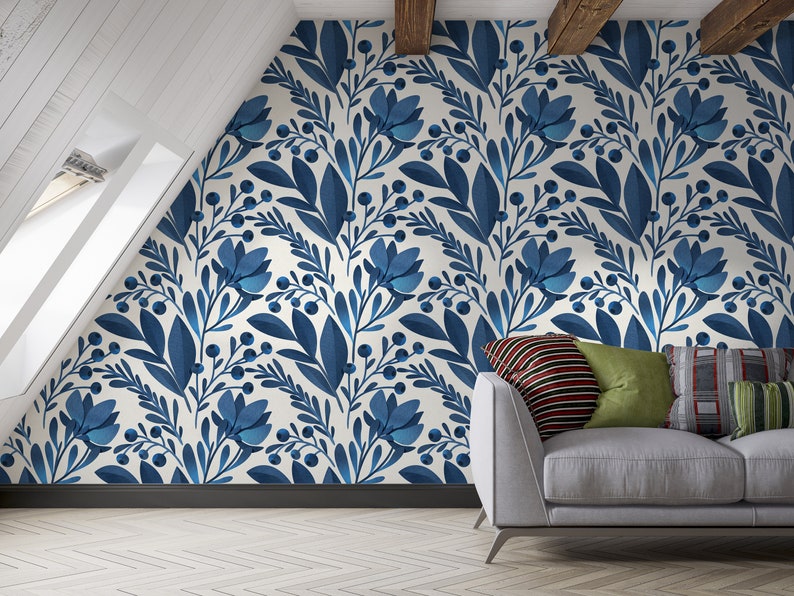 May include: A white wall with a blue floral pattern wallpaper. A gray couch with pillows is in front of the wall.