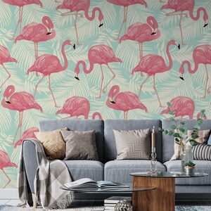 May include: A living room scene featuring a light blue sofa with decorative pillows and a wooden coffee table. The wall behind the sofa is covered in wallpaper with a repeating pattern of pink flamingos and white palm leaves.
