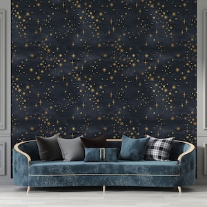 May include: A dark blue velvet sofa with gold trim sits in front of a wall with a navy blue and gold star pattern wallpaper. The sofa has several throw pillows in various patterns and colors.