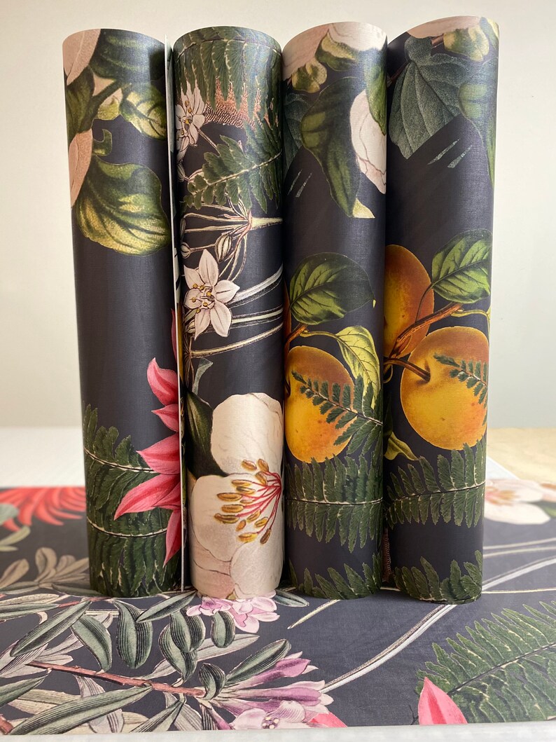 May include: Four rolls of black wrapping paper with a floral and fruit design. The paper features a variety of flowers, ferns, and fruits in shades of green, pink, white, and yellow.
