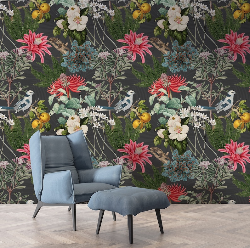 May include: A dark gray wallpaper with a floral pattern featuring white, pink, and blue flowers, green leaves, and yellow fruit. The wallpaper is accented with small blue birds. A blue armchair and ottoman are in the foreground.