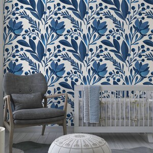 May include: A nursery room with a white crib, a gray armchair, and a white ottoman. The walls are covered in a blue and white floral wallpaper.