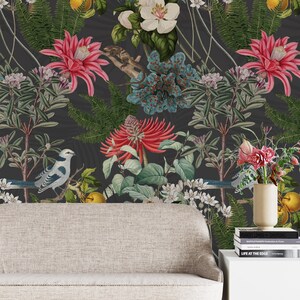 May include: A dark gray wallpaper with a floral pattern featuring white, pink, and blue flowers, green leaves, and yellow fruit. Two blue and white birds are perched on branches. The wallpaper is displayed behind a light gray sofa and a white side table with books.