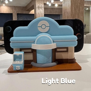 May include: A light blue and brown decorative building with a white accent, resembling a video game shop. The building has a light blue roof with a white circle design. The text "Light Blue" is visible on the surface.
