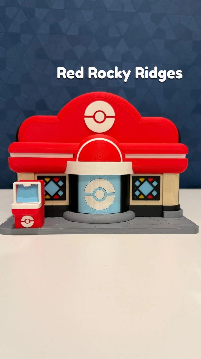 May include: A 3D-printed model of a building with the text "Red Rocky Ridges". The building is primarily red with white and blue accents. It features a central dome and a small vending machine-like structure on the side.