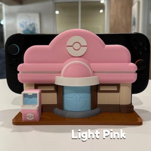 May include: A light pink 3D-printed model of a building with a matching vending machine. The building has a light pink roof with a white and red emblem. The text "Light Pink" is printed on the base.