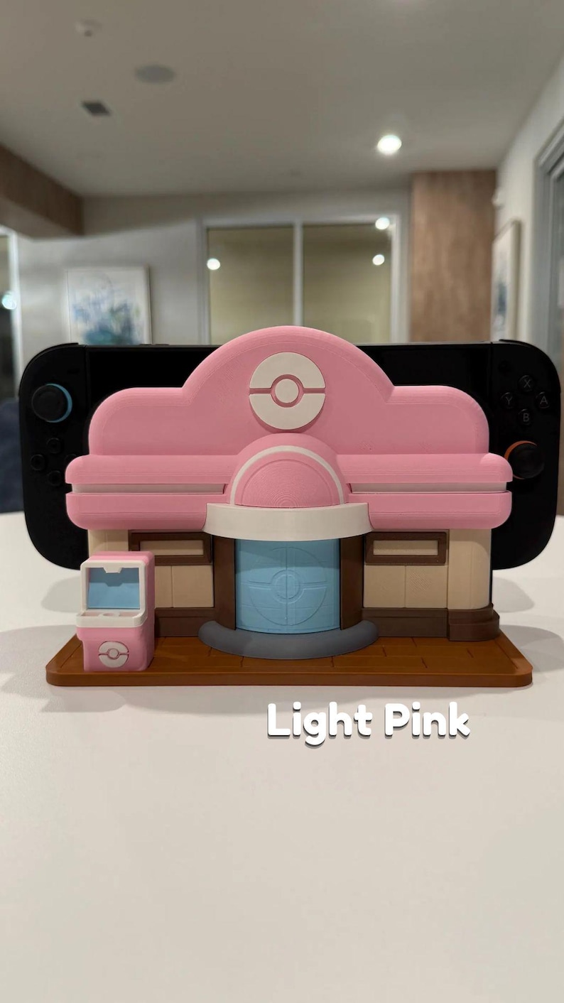 May include: A light pink 3D-printed model of a building with a matching vending machine. The building has a light pink roof with a white and red emblem. The text "Light Pink" is printed on the base.