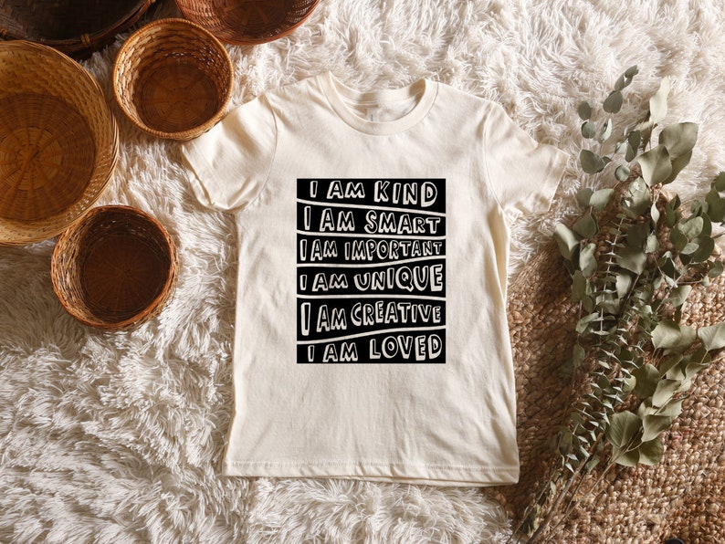 May include: A white t-shirt with a black graphic that reads "I am kind, I am smart, I am important, I am unique, I am creative, I am loved."