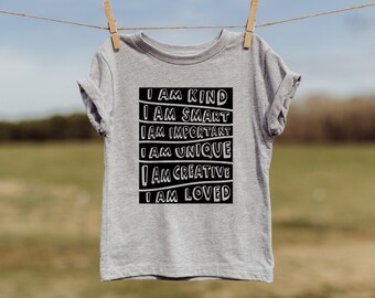 May include: A grey t-shirt with black text that reads "I am kind, I am smart, I am important, I am unique, I am creative, I am loved."