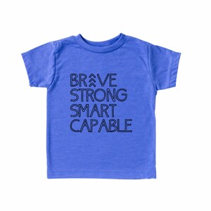 May include: A blue short-sleeved t-shirt with the words "BRAVE STRONG SMART CAPABLE" printed in black on the front.