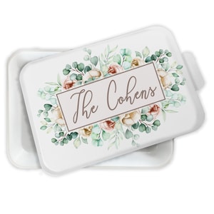 May include: White ceramic baking dish with a lid. The lid features a watercolor design of eucalyptus leaves and pink and white flowers. The text "The Cohens" is written in brown cursive lettering inside a black rectangle.