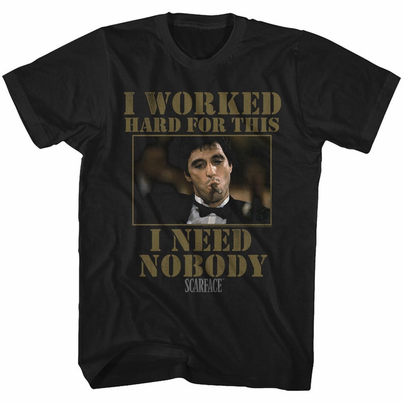 Op de afbeelding: Zwart T-shirt met een gouden afbeelding van Al Pacino als Tony Montana uit de film Scarface. De afbeelding bevat de tekst "I worked hard for this I need nobody Scarface".