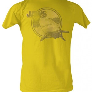 Peut inclure: Un t-shirt jaune avec un graphique de requin et le mot "JAWS" dans un cercle au dos.