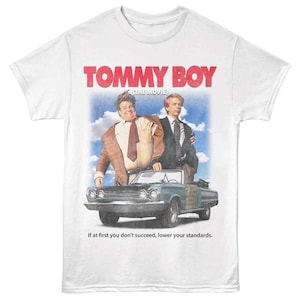 May include: White t-shirt featuring a graphic from the movie "Tommy Boy." The design includes the movie title in red, the film's actors, and a convertible car. The text "If at first you don't succeed, lower your standards" is also included.