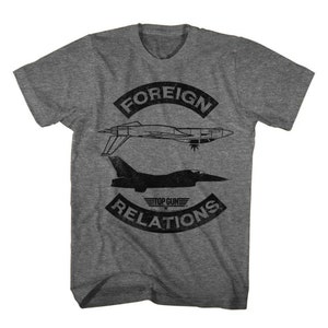 May include: A heather grey t-shirt with a distressed graphic design featuring two fighter jets and the text "FOREIGN RELATIONS" with "TOP GUN" in a smaller font.