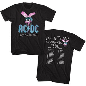 Può includere: Maglietta nera con una mosca di cartone animato blu e rosa e il testo "AC/DC Fly on the Wall". La parte posteriore della maglietta ha un programma di tour per il "Fly on the Wall European Tour 1986".