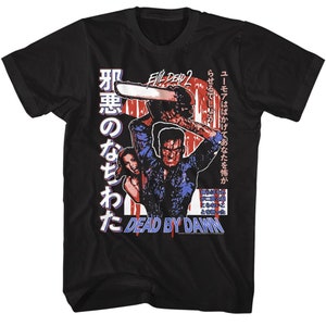 Puede incluir: Camiseta negra con un gráfico de un personaje de la película Evil Dead 2. El personaje sostiene una motosierra y hay salpicaduras de sangre en la camiseta. El texto "Evil Dead 2" y "Dead by Dawn" están en la camiseta.