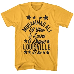 Puede incluir: Una camiseta amarilla con un estampado gráfico negro del récord de boxeo de Muhammad Ali. El gráfico incluye el texto "Muhammad Ali", "56 victorias", "5 derrotas", "0 empates", "Louisville" y "37 KO".