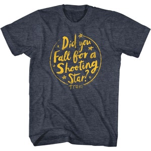May include: A dark blue t-shirt with a gold circle graphic that says "Did you fall for a shooting star?" with a star symbol above and below the text. The text "train" is below the circle.