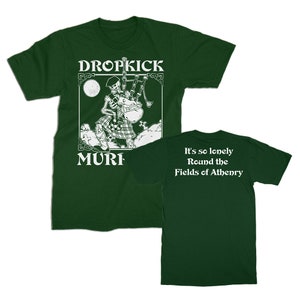 Pode incluir: Uma camiseta verde com um gráfico branco de um esqueleto tocando gaita de foles. O texto "DROPKICK MUR" está abaixo do gráfico. A parte de trás da camiseta tem o texto "It's so lonely Round the Fields of Athenry".