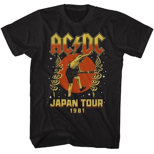 May include: Black t-shirt with a yellow and orange graphic of a rock band performing on stage. The graphic includes the band's name "AC/DC" and the text "Japan Tour 1981".