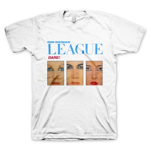 Puede incluir: Camiseta blanca con un gráfico azul y blanco de la banda The Human League. El gráfico incluye el nombre de la banda y la palabra "Dare!" en texto azul. Se muestran tres rostros de mujeres en el gráfico.