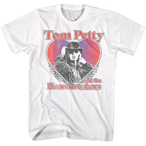 Puede incluir: Camiseta blanca con un gráfico de estilo vintage de Tom Petty and the Heartbreakers. El gráfico presenta un corazón rojo con una silueta de Tom Petty con un sombrero, y el nombre de la banda en texto rojo.