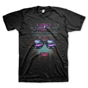 Könnte beinhalten: Schwarzes T-Shirt mit einem Grafikdruck eines Gesichts mit Sonnenbrille und dem Text "A Flock of Seagulls" in Weiß.