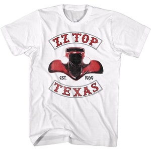 Può includere: Maglietta bianca con una grafica rossa, bianca e nera di un'auto d'epoca con il testo "ZZ TOP" sopra l'auto e "EST. 1969 TEXAS" sotto l'auto.