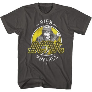 May include: A dark grey t-shirt with a yellow circle graphic featuring a man playing a guitar. The graphic says "HIGH VOLTAGE" and "AC/DC" in yellow letters.