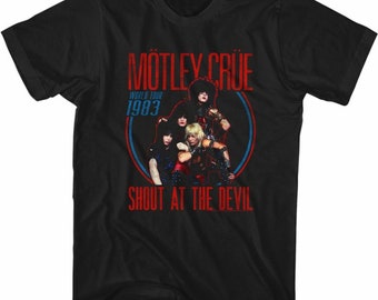 Puede incluir: Camiseta negra con un gráfico rojo y azul de la banda Motley Crue. El gráfico incluye el nombre de la banda, el texto "World Tour 1983" y el texto "Shout at the Devil".