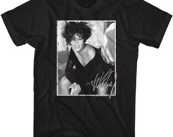May include: Black t-shirt featuring a black and white image of a woman in a black dress. The image includes a signature in white. The t-shirt is a classic crew neck style.