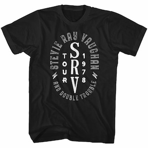 May include: Black t-shirt with a white circle graphic featuring the text "Stevie Ray Vaughan" and "SRV" with an eye chart design. The text "And Double Trouble" is written around the bottom of the circle.