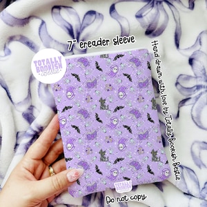 May include: A 7-inch ereader sleeve featuring a repeating pattern on a light purple background. The design includes illustrations of purple books, black cats, ghosts, bats, and glass bottles. The text "TOTALLY BOOKISH Bestie" is visible.