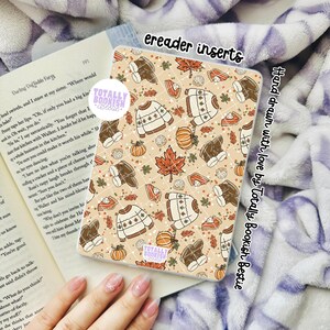 May include: An ereader insert featuring a repeating pattern of autumn-themed illustrations including sweaters, pumpkins, boots, and pie slices on a light tan background. The text "ereader inserts" and "Hand drawn with love by Totally Bookish Bestie" is visible.