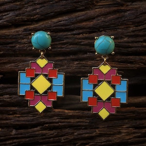 May include: A pair of geometric earrings with a turquoise stone at the top. The earrings are made of gold metal and have a colorful geometric design with red, yellow, blue, and pink accents.