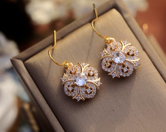 May include: A pair of gold-tone earrings with a floral design and clear cubic zirconia stones.