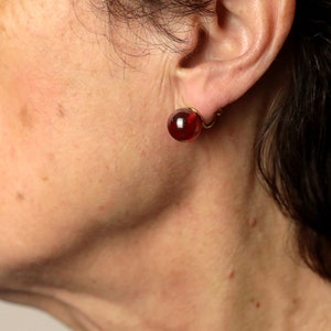 May include: A pair of red glass earrings with gold-toned metal clasps.