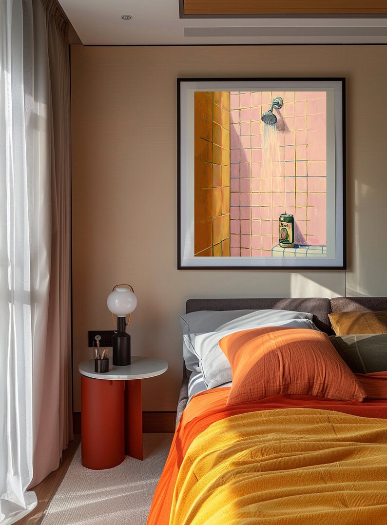 May include: A framed artwork depicts a shower scene with pink tiles and a beer can. The bedroom setting includes a bed with orange and yellow bedding, a side table with a lamp, and a window with sheer curtains.