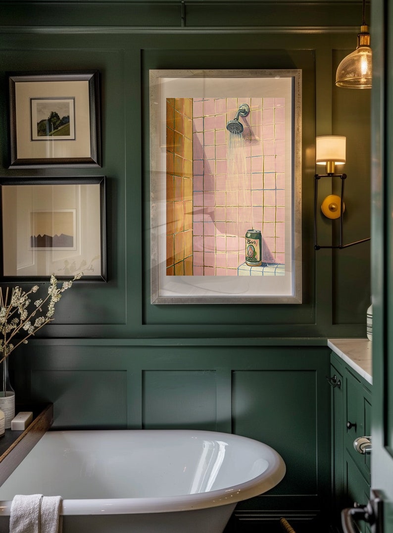 May include: A bathroom scene with a large white bathtub and a framed artwork depicting a shower with a beer can. The walls are dark green, and there are two framed pictures above the tub. A wall sconce provides additional lighting.