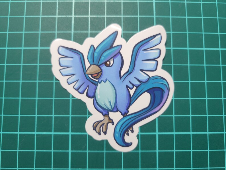 May include: A blue and white cartoon sticker of a bird-like Pokemon with a long tail and wings spread out.