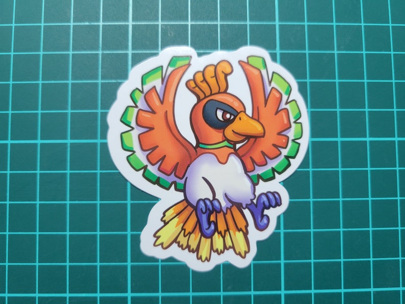 May include: A sticker featuring a cartoon illustration of a red, orange, green, and yellow bird with a white body and a green and white head. The bird is flying with its wings spread out.