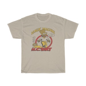 May include: A beige t-shirt featuring a cartoon image of Bart Simpson as a rapper. The image is within a red circle with the text "Dancin' Machine" above and "M.C. Bart" below. The text inside the circle reads "You can't touch this!"