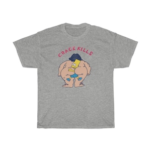 May include: A grey t-shirt featuring a cartoon image of a yellow character wearing a blue shirt and black hair. The text "CRACK KILLS" is printed in pink above the image.