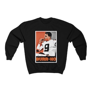 Op de afbeelding: Zwart sweatshirt met een afbeelding van een voetballer die een wit shirt draagt met nummer 9. De afbeelding is in een rood en oranje kader met de tekst "BURR-HO" eronder.