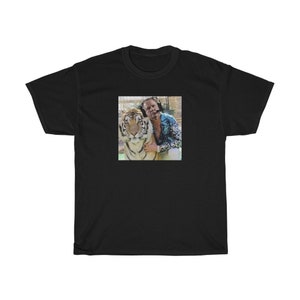 May include: A black t-shirt with a photo of a man with a tiger. The man is wearing a blue and white patterned shirt and the tiger is looking at the camera.