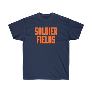 Könnte beinhalten: Marineblaues T-Shirt mit dem orangefarbenen Schriftzug "SOLDIER FIELDS". Der Text ist fett und zentriert. Das T-Shirt hat einen Rundhalsausschnitt und kurze Ärmel. Der Stoff ist einfarbig.