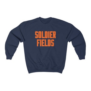 Könnte beinhalten: Ein marineblauer Pullover mit dem Aufdruck "SOLDIER FIELDS" in Orange auf der Vorderseite.
